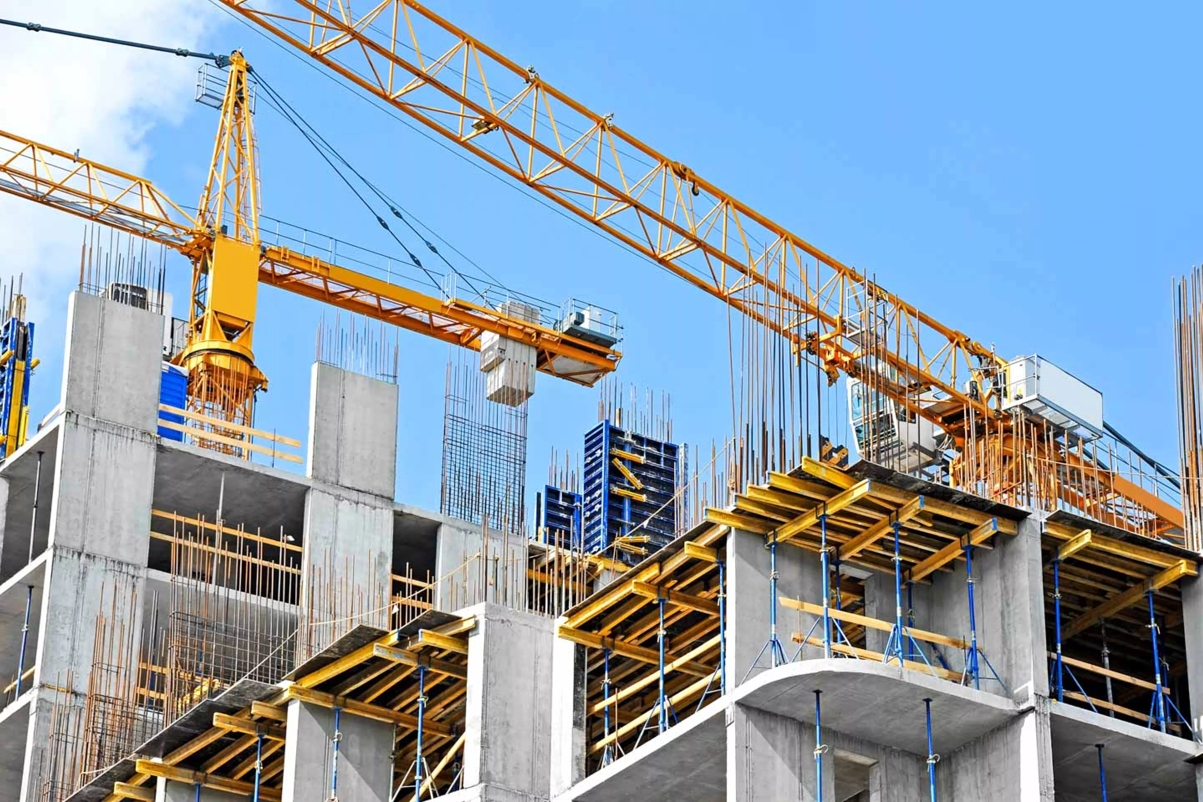 Crane and building construction site against blue sky