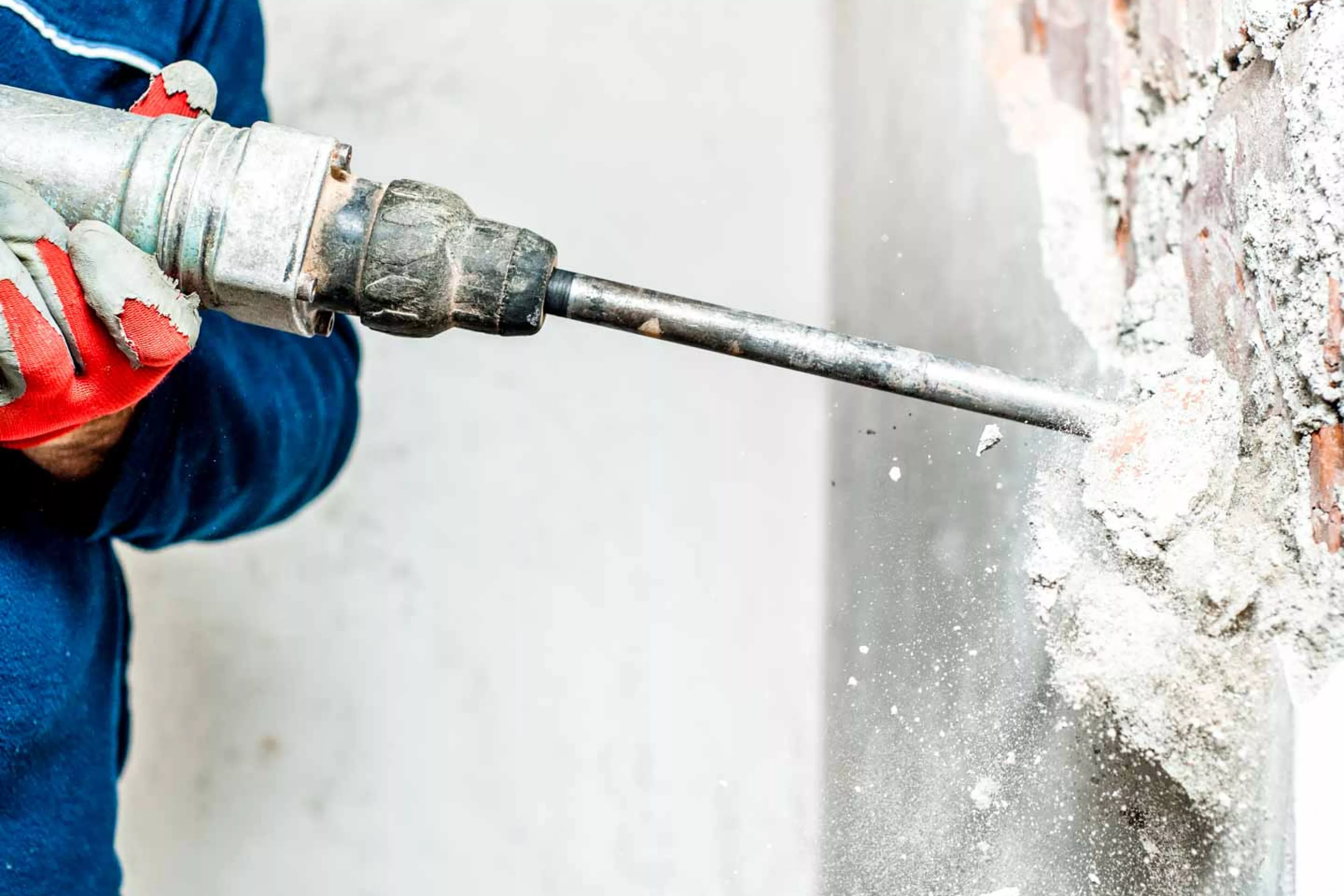 Construction worker uses drill on concrete wall