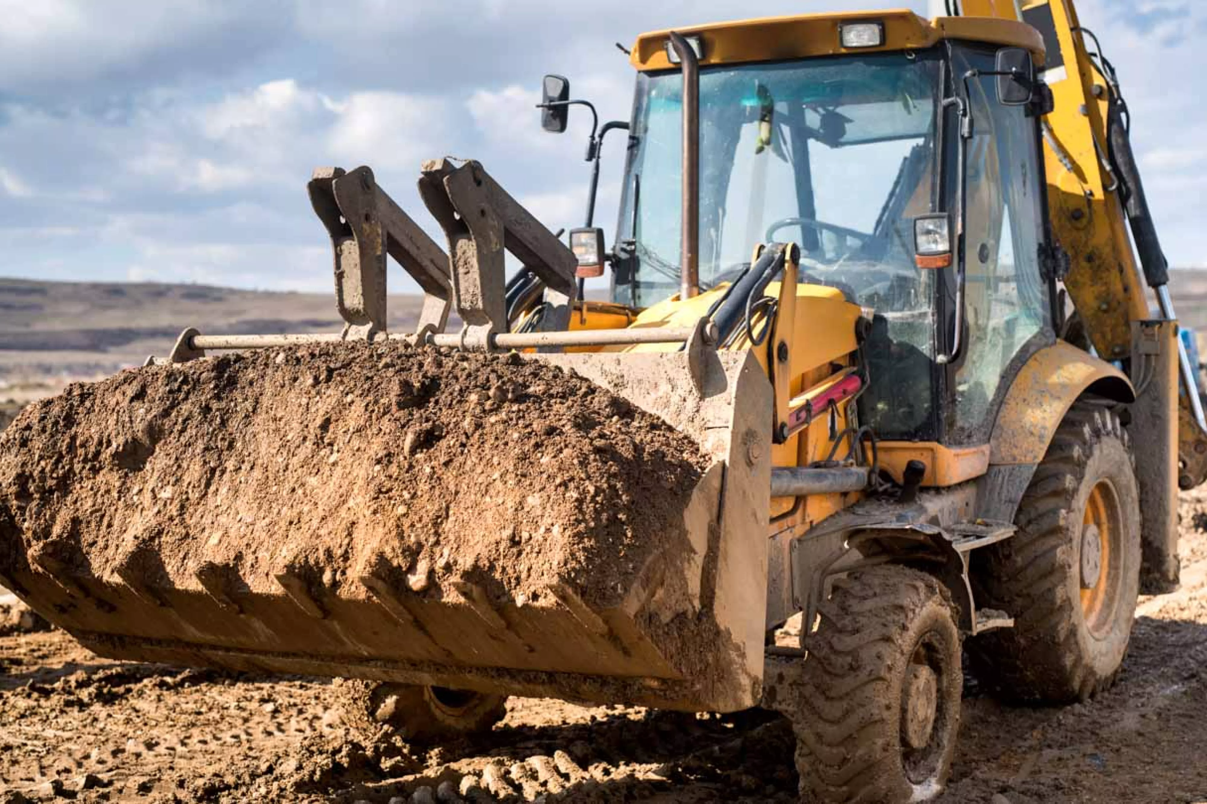 Industrial backhoe with bucketful of dirt