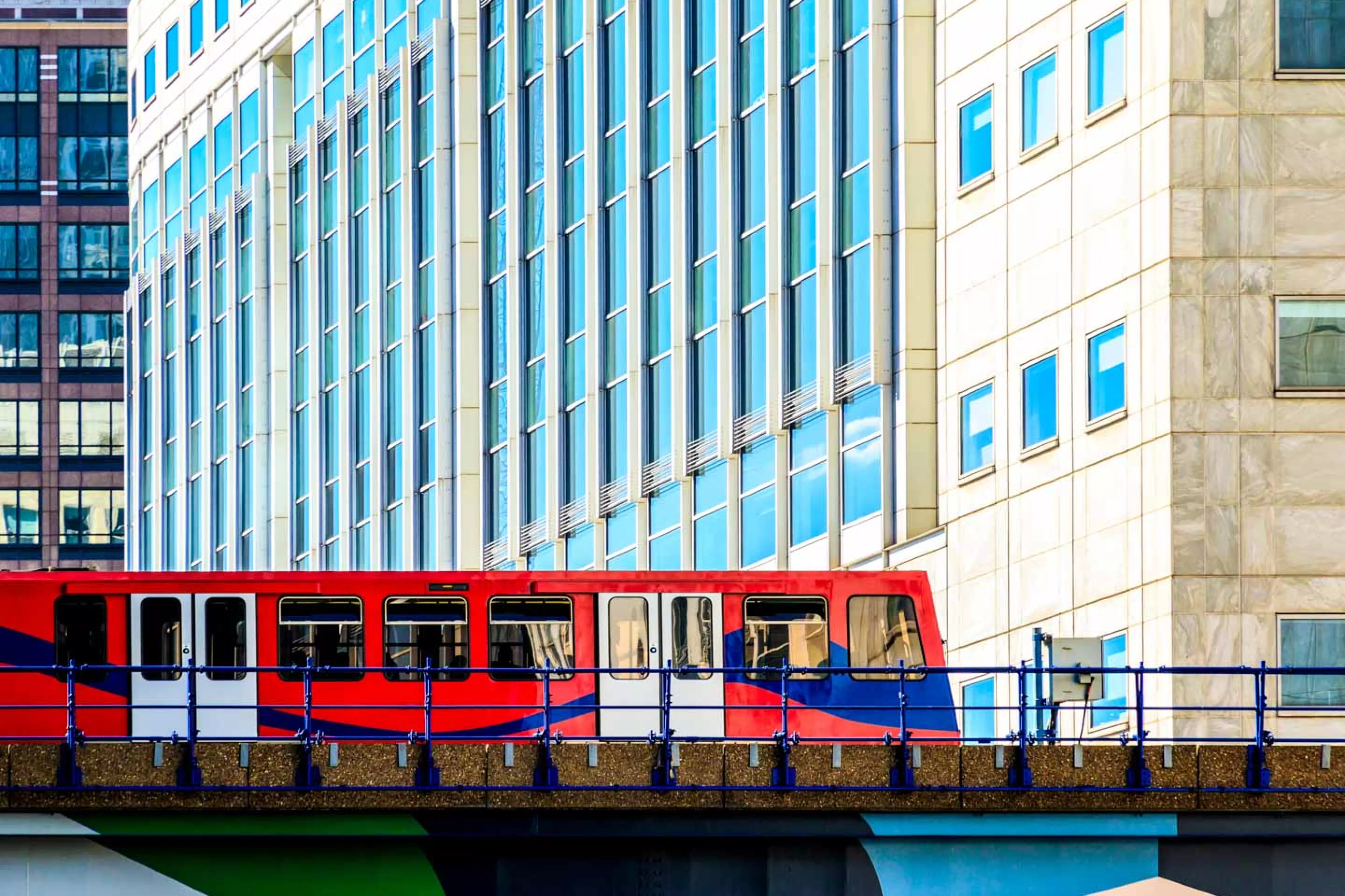 Red train crosses city bridge