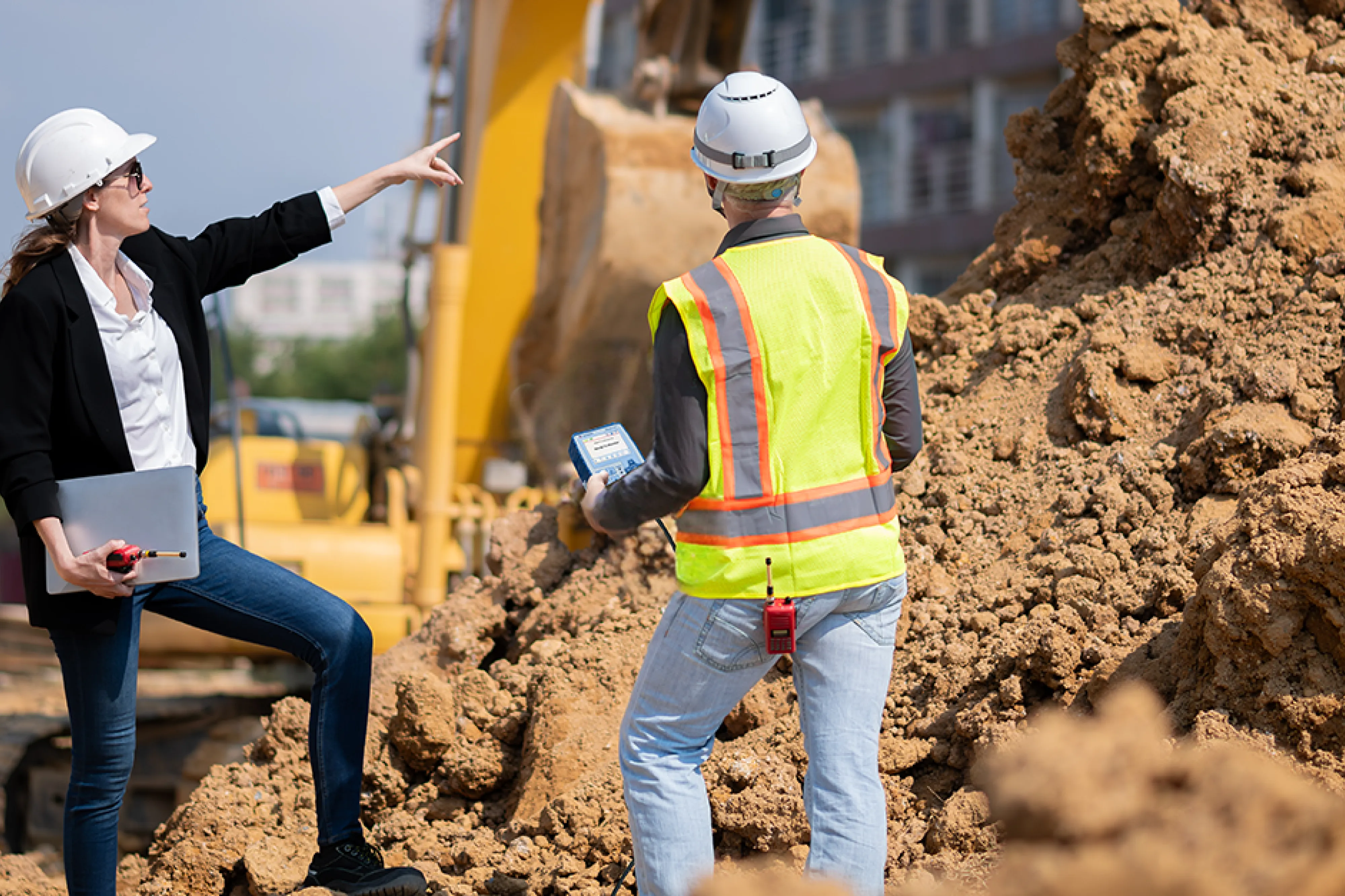 Two construction workers discussing a project. One holds a Micromate.
