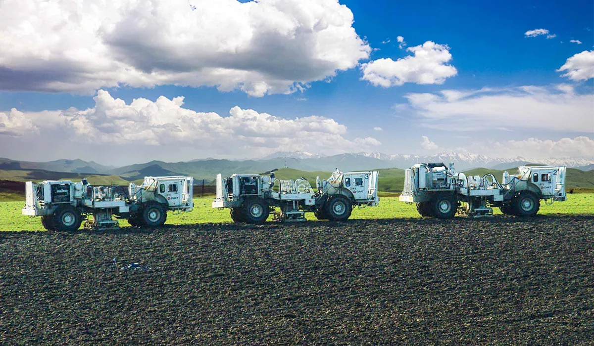 Three vibraseis trucks on edge of field